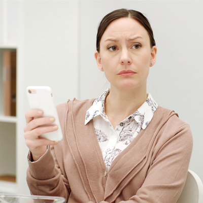 En kvinna h&aring;ller i en mobiltelefon och tittar bekymrat upp